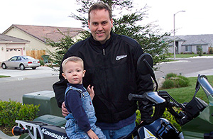 Motorcycle lawyer Frank Penney and his son sitting on a motorcycle outside their home