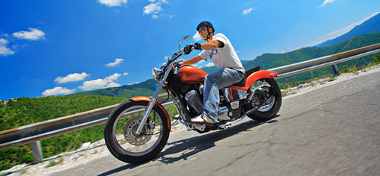 A male motorcyclist leisurely riding through mountains. Buying a new or used motorcycle can change your riding experience for better or worse